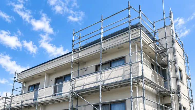 足場を組んで外壁を塗り替えている建物のイメージ。